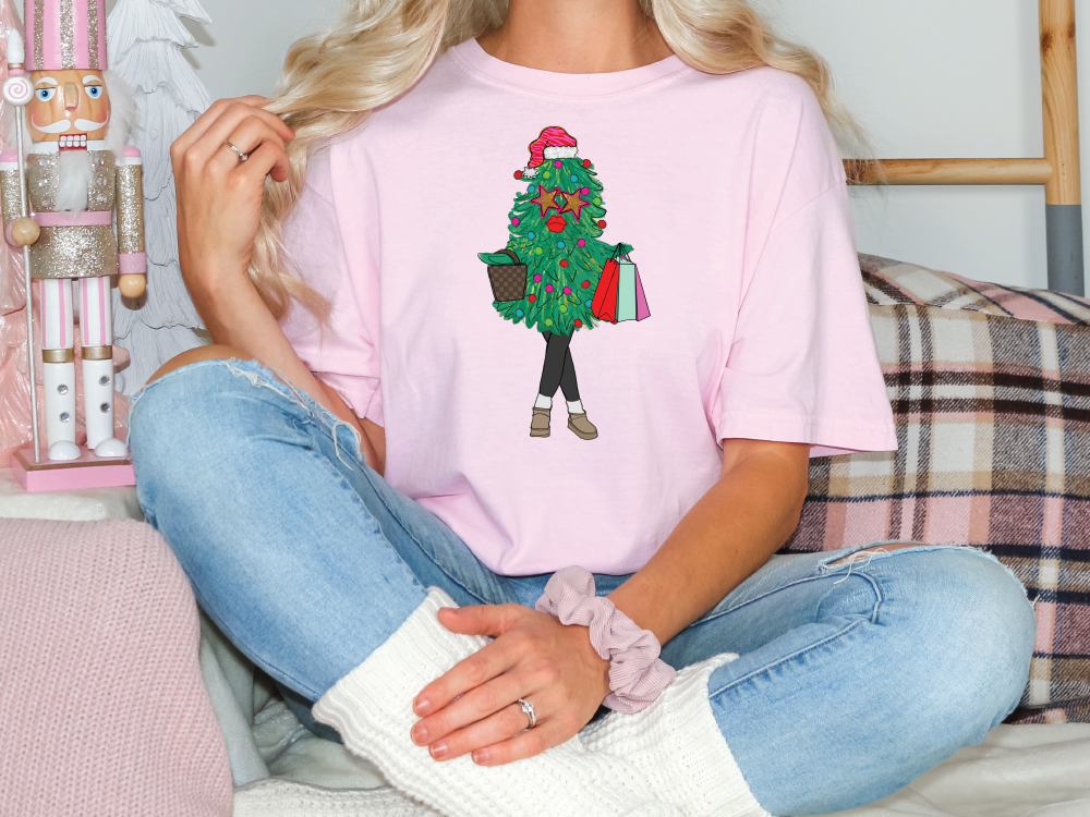 a woman sitting on a couch wearing a pink shirt with a christmas tree on it