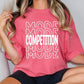 a woman wearing a pink t - shirt that says more competition mode