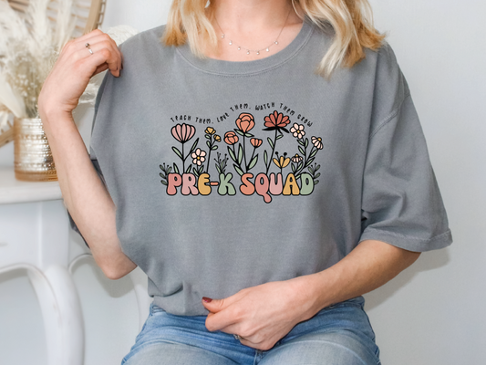 a woman sitting on a chair wearing a grey t - shirt that says pre k