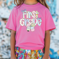a little girl wearing a pink shirt and colorful shorts