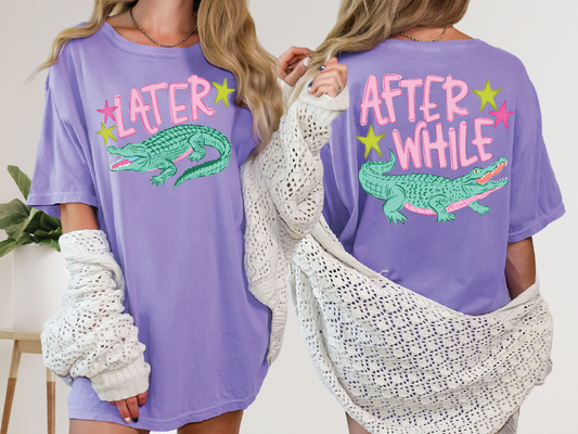 two women wearing purple t-shirts with a graphic of a green alligator and the text "LATER" and "AFTER WHILE" printed on them.