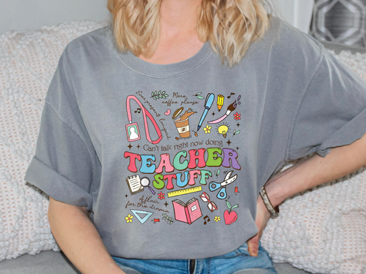 a woman sitting on a couch wearing a teacher stuff t - shirt