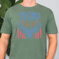 a man standing in front of a plant wearing a trump t - shirt