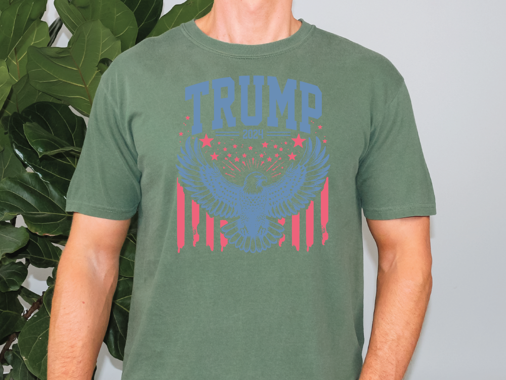 a man standing in front of a plant wearing a trump t - shirt