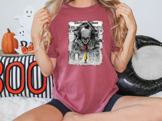 a woman sitting on a bed holding up a t - shirt