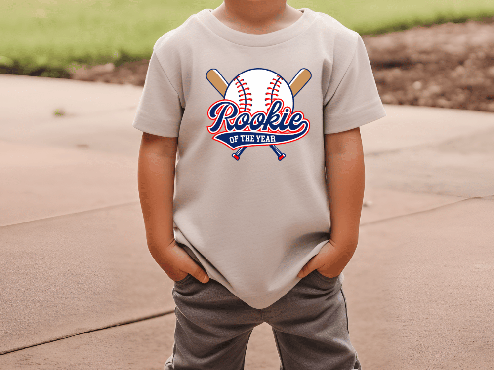 A child wearing a white t-shirt with a baseball graphic and the text "Rookie of the Year" printed on it.