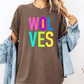 A person wearing a brown t-shirt with the text "WOLVES" in colorful letters, paired with a denim jacket, stands against a white background.