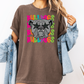 A woman wearing a brown t-shirt with a graphic of a bulldog and colorful text surrounding it.