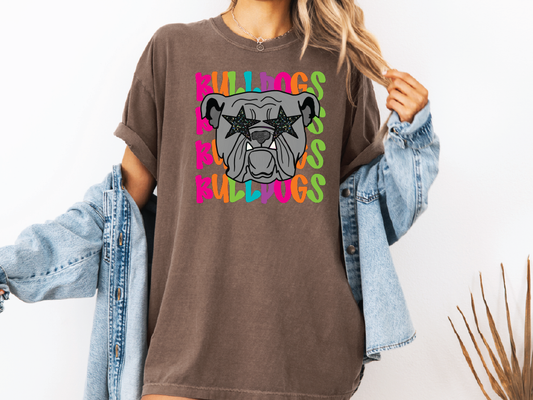 A woman wearing a brown t-shirt with a graphic of a bulldog and colorful text surrounding it.