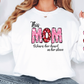 a woman wearing a white shirt that says, this mom wears her heart on her