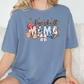 a woman sitting on a couch wearing a baseball mom shirt