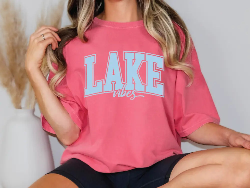 a woman sitting on a chair wearing a pink lake days shirt