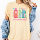A woman wearing a yellow t-shirt with a graphic design of three colorful gas pumps and the text "That's my husband's problem" printed on it.