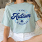 a woman sitting on a bed wearing an autism t - shirt