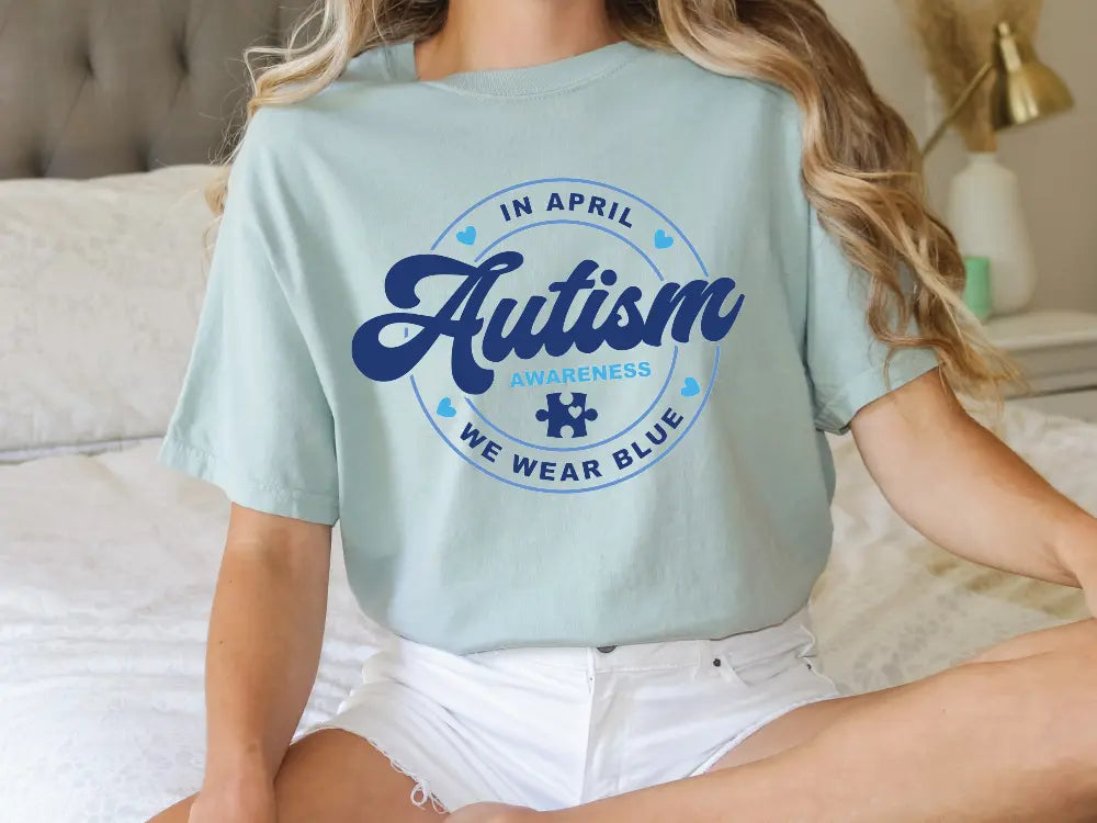 a woman sitting on a bed wearing an autism t - shirt