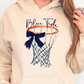 a woman wearing a blue tide hoodie holding a basketball hoop