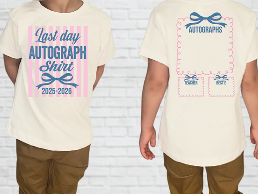 a white t-shirt with a graphic design on the front and back. The front of the t-shirt displays a pink and blue striped pattern with the text "Last day autograph shirt" and "2025-2026". The back of the t-shirt has a pink and blue ribbon design with the text "Autographs" and "Teacher" written on it.
