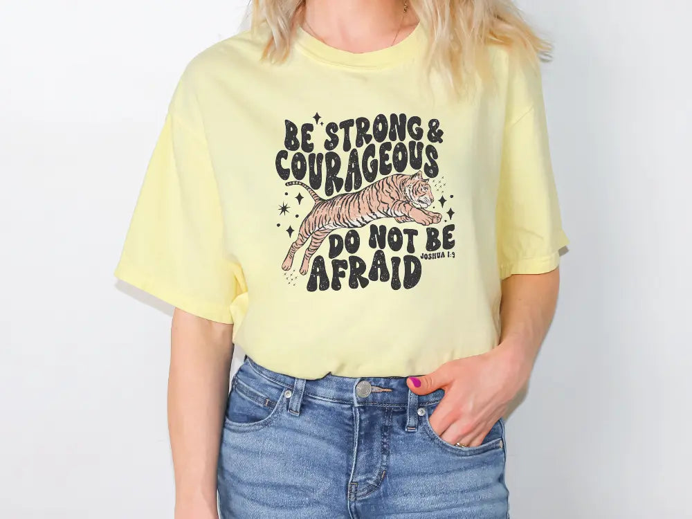 a woman wearing a yellow shirt that says be strong and courageous