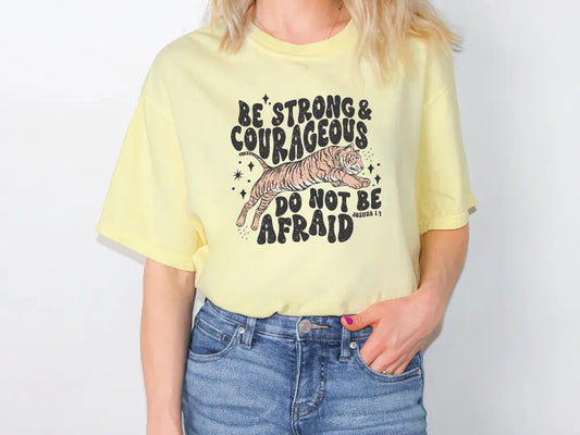 a woman wearing a yellow shirt that says be strong and courageous