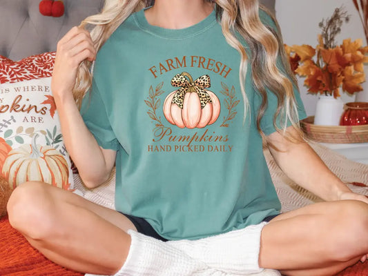 a woman sitting on a bed with a pumpkin on her shirt