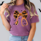 A woman wearing a purple t-shirt with a Halloween-themed graphic design, including a large bow, bats, and a pumpkin.