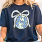 A woman wearing a blue t-shirt with a graphic design of a bow and snowflakes on it.