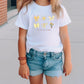 a little girl wearing a white shirt and denim shorts