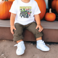 a young boy sitting in front of pumpkins