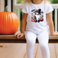 a little girl sitting on a bench next to a pumpkin