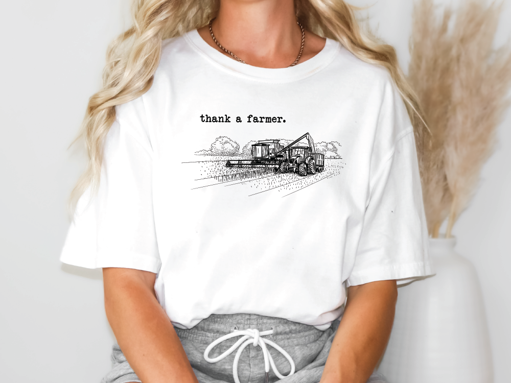 a woman wearing a white t - shirt with a tractor drawn on it