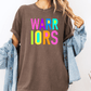 A person wearing a brown t-shirt with the text "WARRIORS" in colorful letters, paired with a denim jacket.