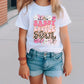 a little girl wearing a white shirt and denim shorts