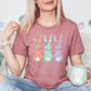 A woman wearing a pink t-shirt with a bunny design is sitting on a couch, holding a mug and smiling.