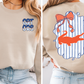 The image is a collage of two photos. The left photo shows a person wearing a beige sweater with a blue and white striped design on the front, featuring a graphic of a cat. The right photo shows the back of the same sweater, with a graphic of a cat and a bow on the back.