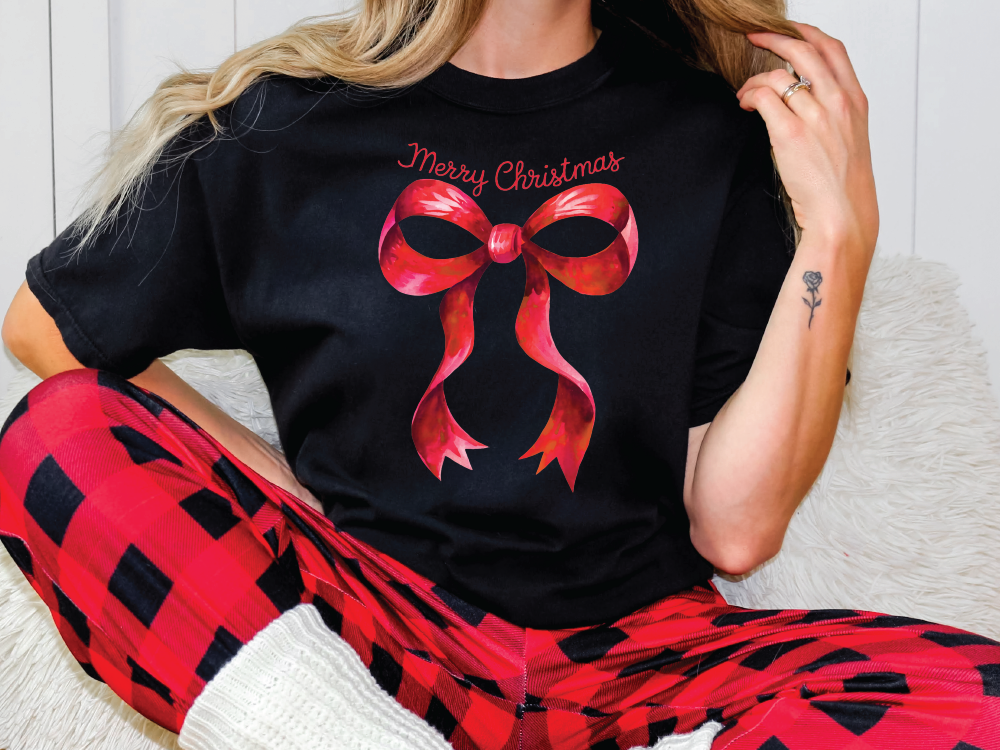 a woman sitting on a couch wearing a black shirt with a red bow on it