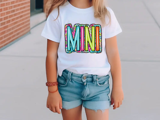 a little girl wearing a white shirt with the word mini on it