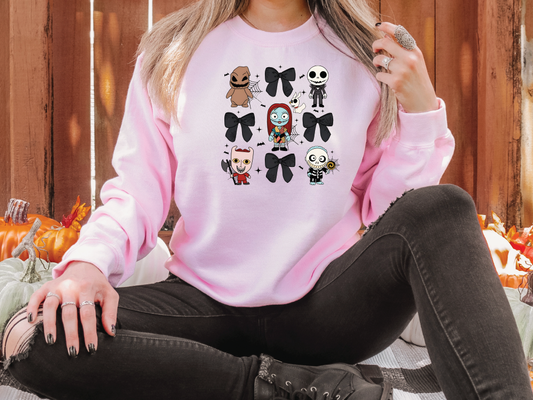 a woman sitting on the ground wearing a pink sweater with a bunch of halloween characters