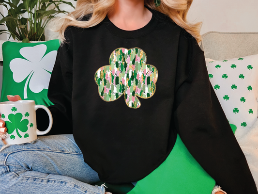 a woman sitting on a couch wearing a black sweater with a shamrock on it