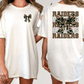 A woman wearing a white t-shirt with a camouflage design and the word "RAIDERS" printed on the back.