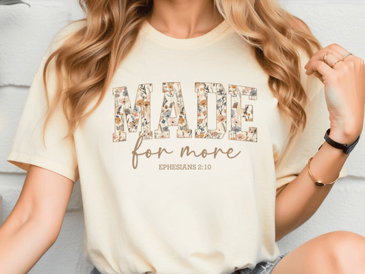 A woman wearing a white t-shirt with the text "MADE for more" printed on it.