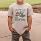 A child wearing a white t-shirt with a graphic design of a duck and the text "Flying into 100 days of school" printed on it.