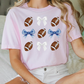 a woman sitting on a bed wearing a pink shirt with footballs on it