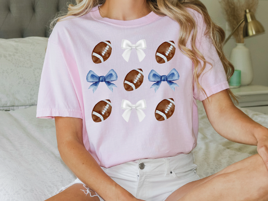 a woman sitting on a bed wearing a pink shirt with footballs on it
