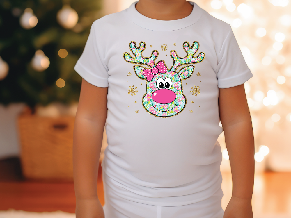 a little girl wearing a white shirt with a reindeer head on it