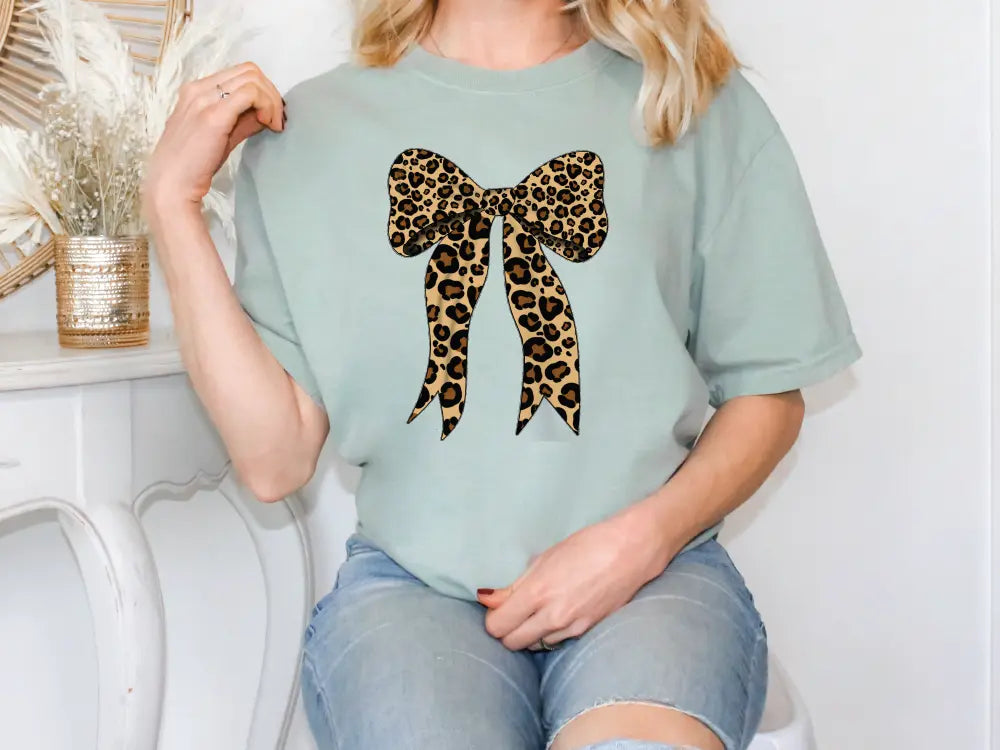 a woman sitting on a chair wearing a t - shirt with a bow on it