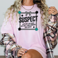 a woman wearing a pink tshirt with the words suspect on it