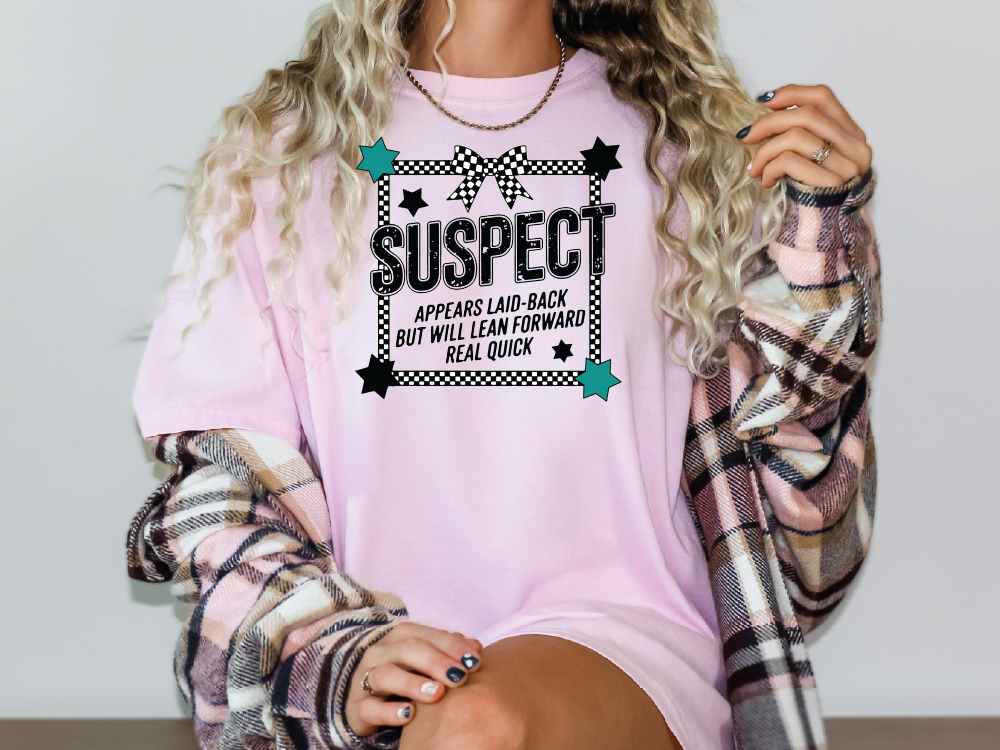 a woman wearing a pink tshirt with the words suspect on it