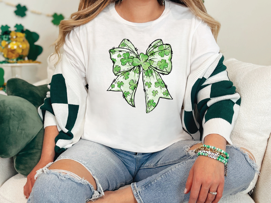 a woman sitting on a couch wearing a white shirt with a green bow on it