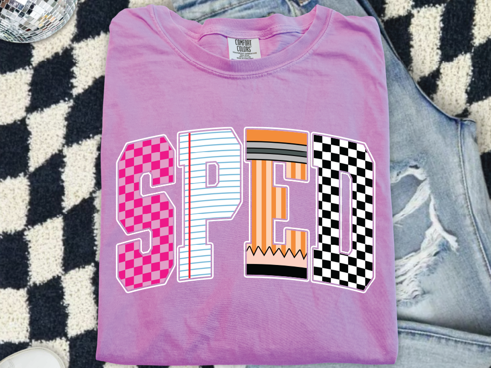 A pink t-shirt with the word "SPED" printed on it, along with a graphic design that includes a pencil and a checkered pattern.