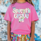 a little girl wearing a pink shirt that says seventh grade